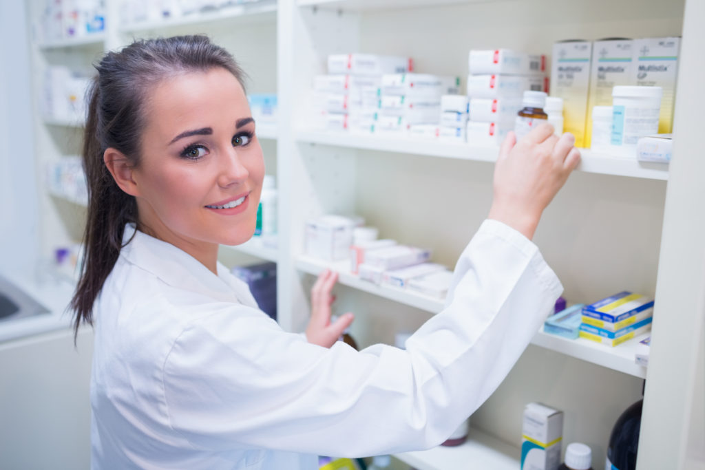 Smiling pharmacist taking jar from shelf in the pharmacy