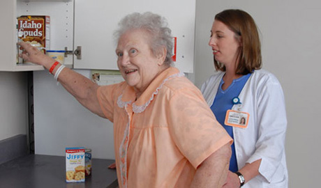 Elderly women getting food from a cabinet as part of her occupational therapy